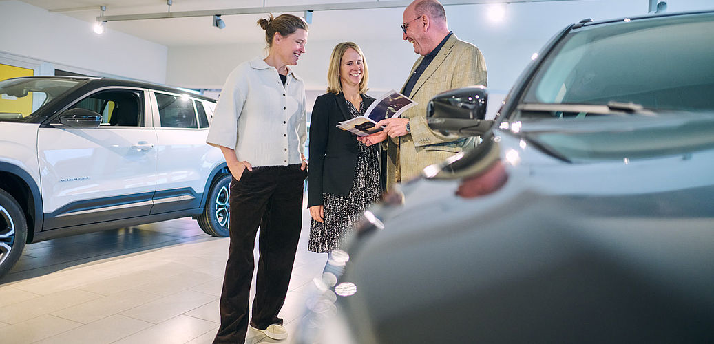 Alle drei Geschäftsführer blättern gemeinsam durch ein Prospekt