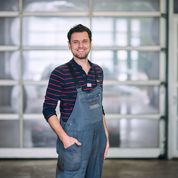 Werkstattmitarbeiter lächelt in die Kamera in der Werkstatt