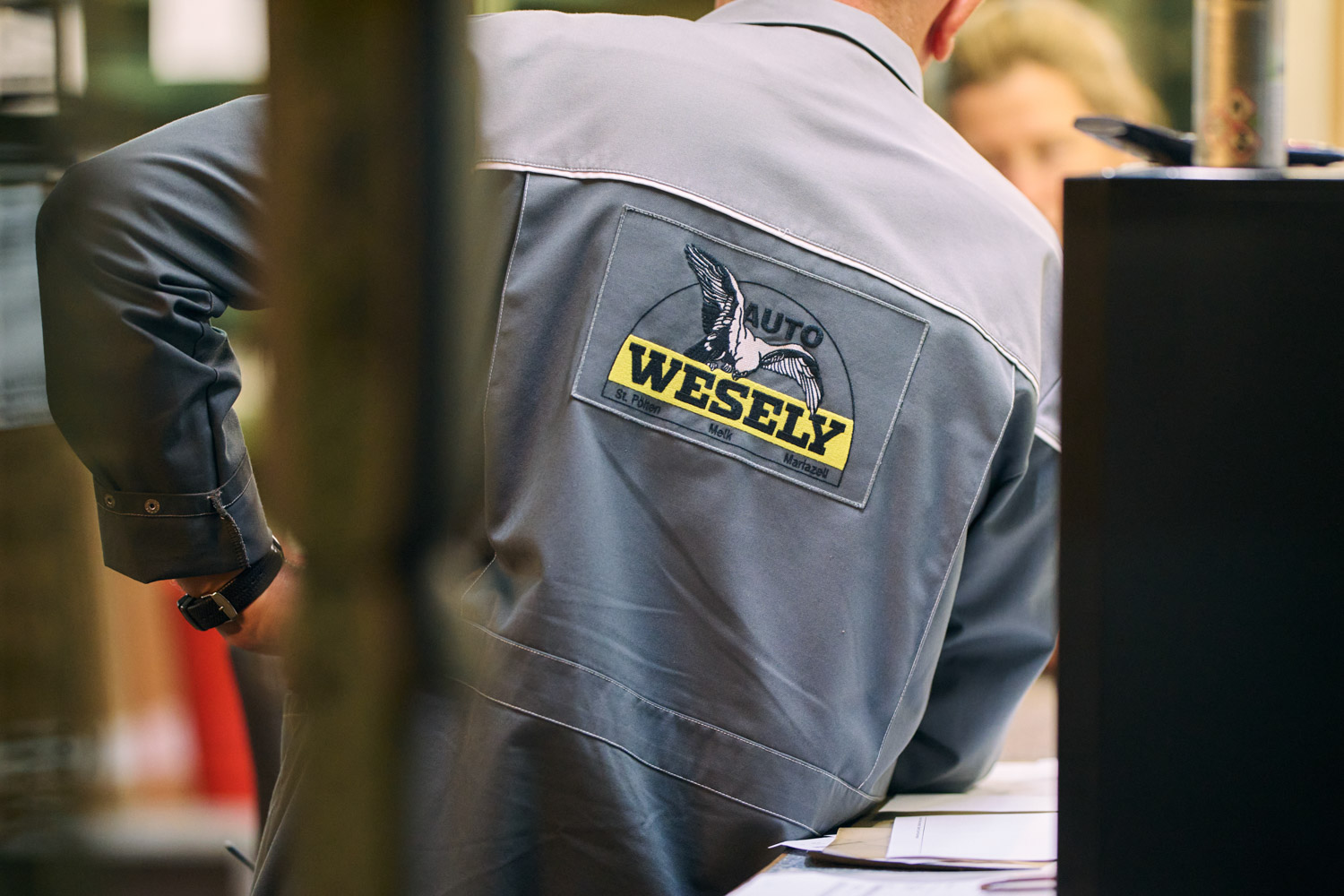 Rückseite der Arbeitskleidung mit Firmenlogo, getragen von einem Mitarbeiter.